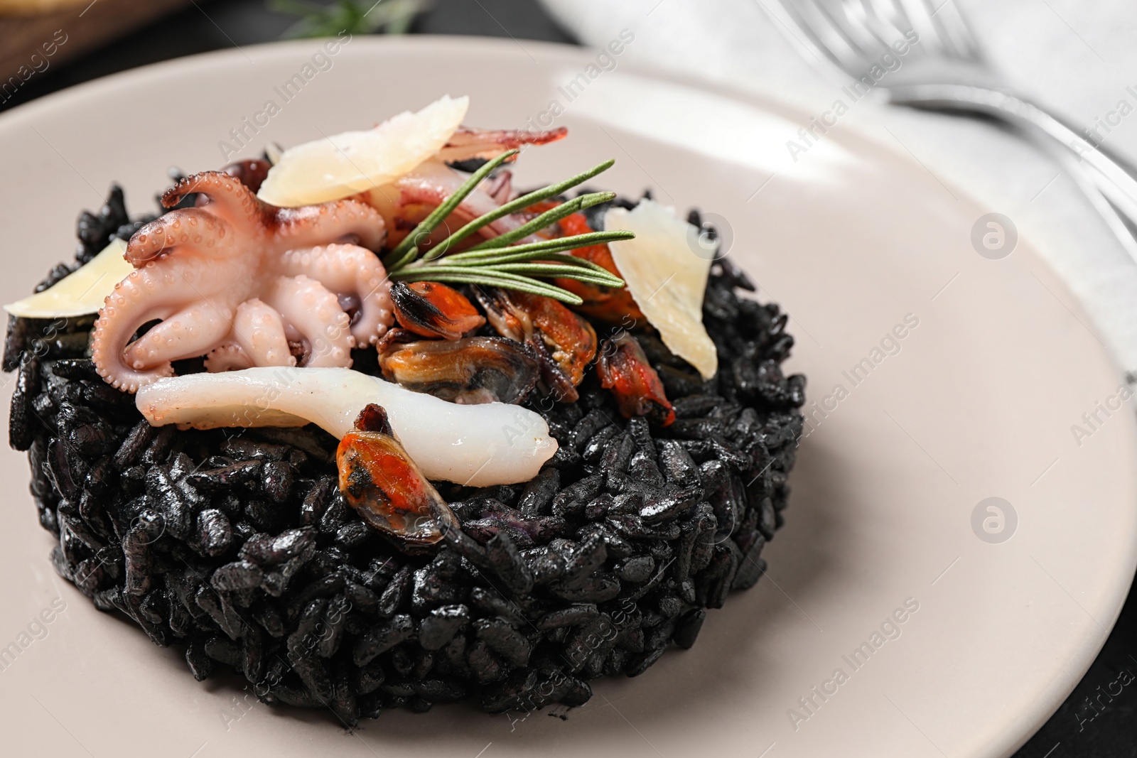 Photo of Delicious black risotto with seafood in plate, closeup