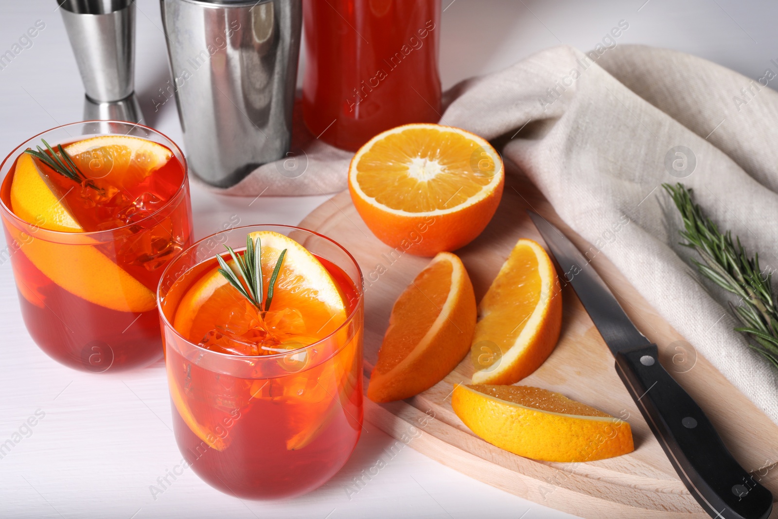 Photo of Aperol spritz cocktail, rosemary and orange slices on white wooden table