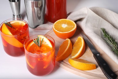 Photo of Aperol spritz cocktail, rosemary and orange slices on white wooden table