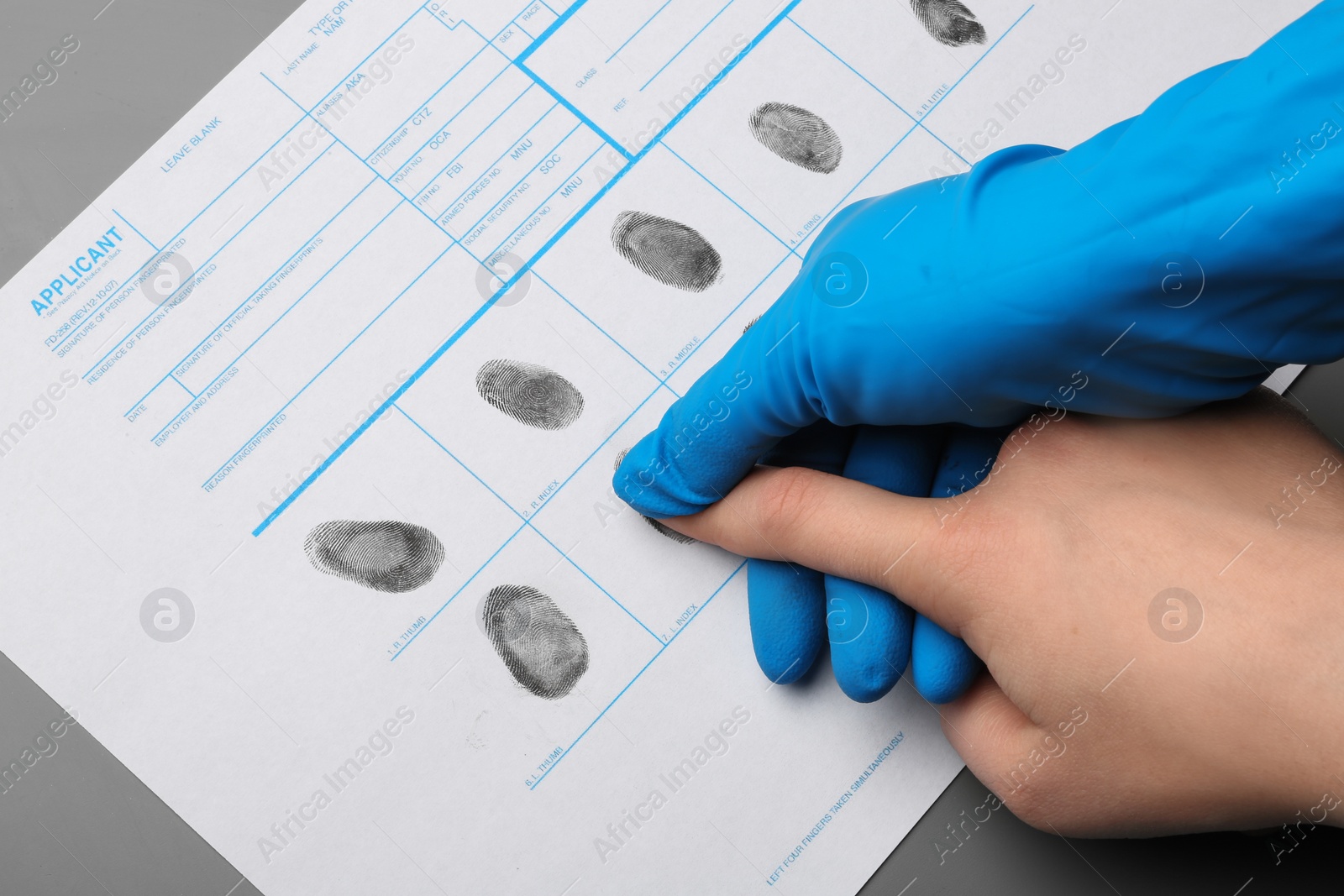 Photo of Investigator taking fingerprints of suspect at table, closeup. Criminal expertise