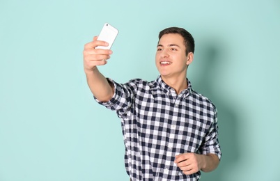 Young handsome man taking selfie against color background