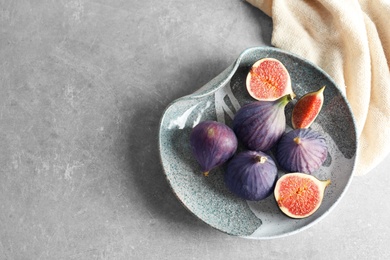 Photo of Plate with fresh ripe figs on gray background, top view. Space for text