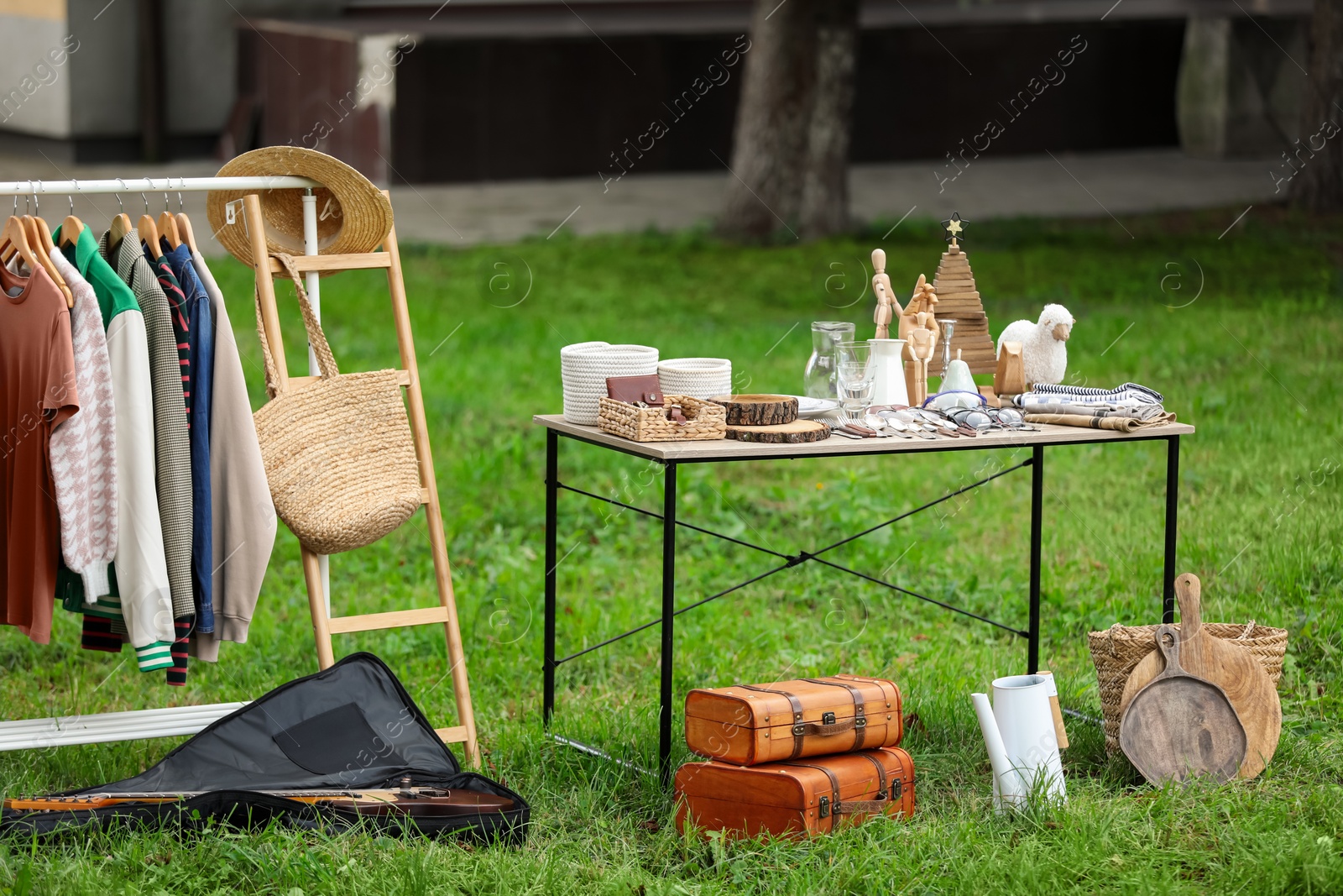 Photo of Table with many different items on grass in yard. Garage sale