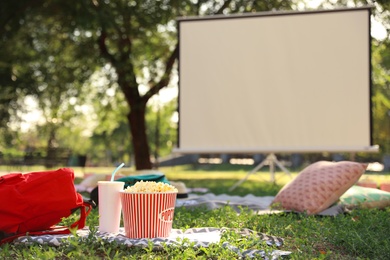 Photo of Popcorn and drink on green grass in open air cinema. Space for text