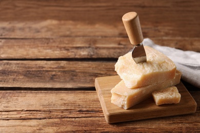Photo of Delicious parmesan cheese with knife on wooden table. Space for text