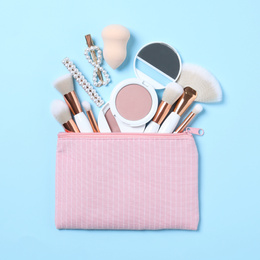 Cosmetic bag with makeup products and beauty accessories on light blue background, flat lay