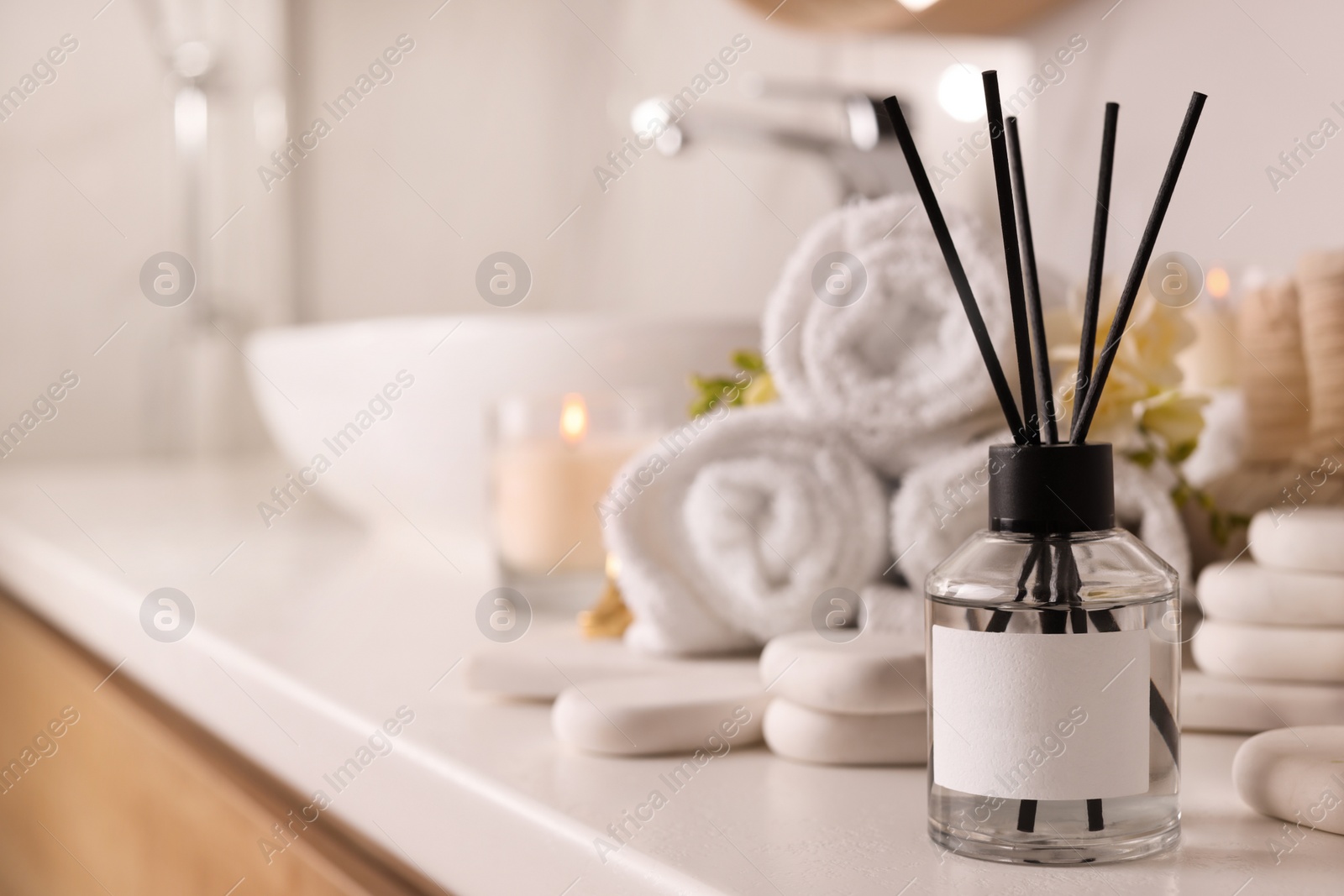 Photo of Aromatic reed air freshener and spa stones on white table, space for text