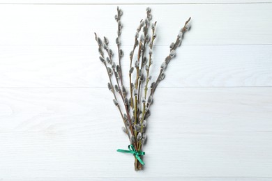 Beautiful bouquet of pussy willow branches on white wooden background, top view