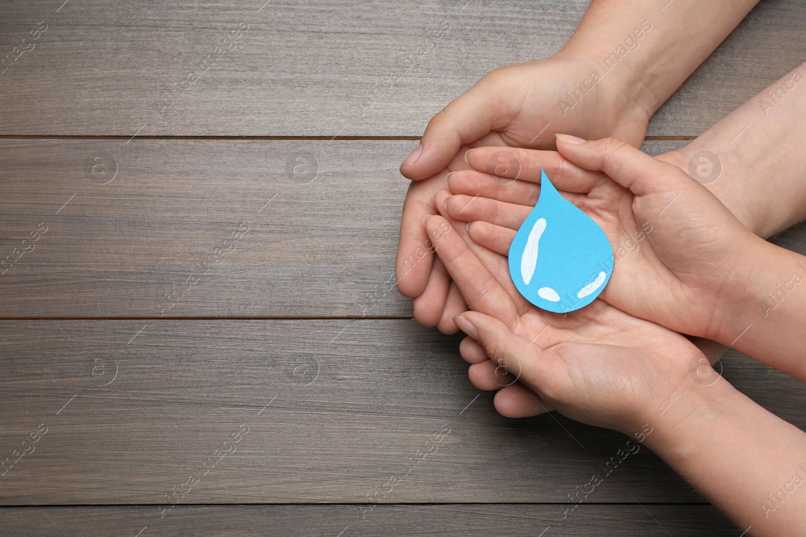 Photo of Save Water concept. Man and woman holding paper drop at wooden table, top view with space for text