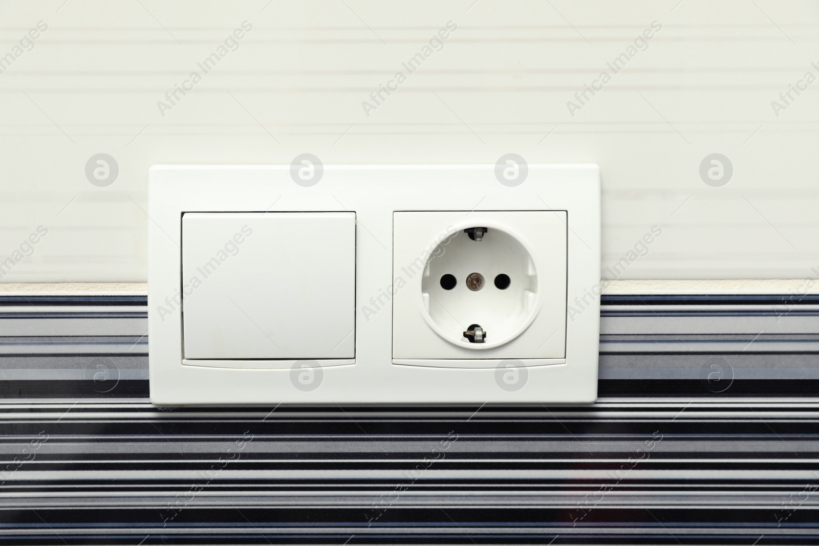 Photo of Modern plastic light switch and socket on color wall, closeup