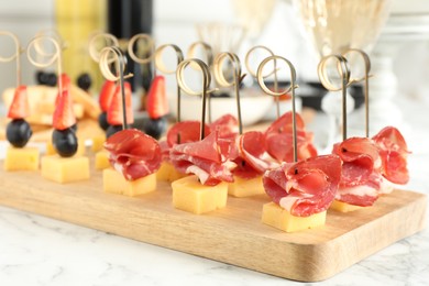 Different tasty canapes on white marble table, closeup