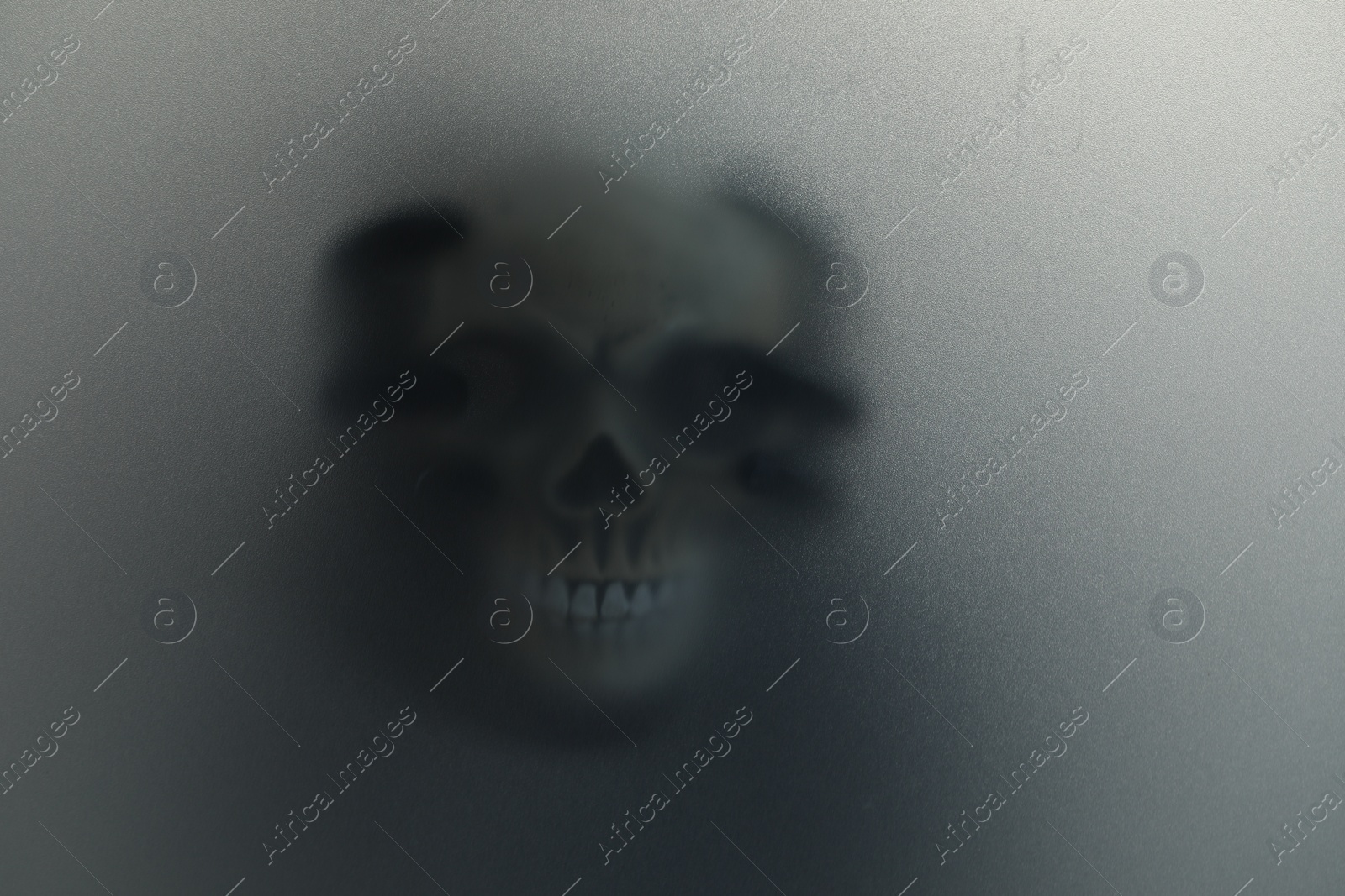 Photo of Silhouette of creepy ghost with skull behind cloth