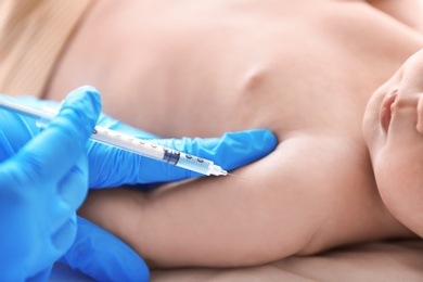 Doctor vaccinating baby in clinic, closeup