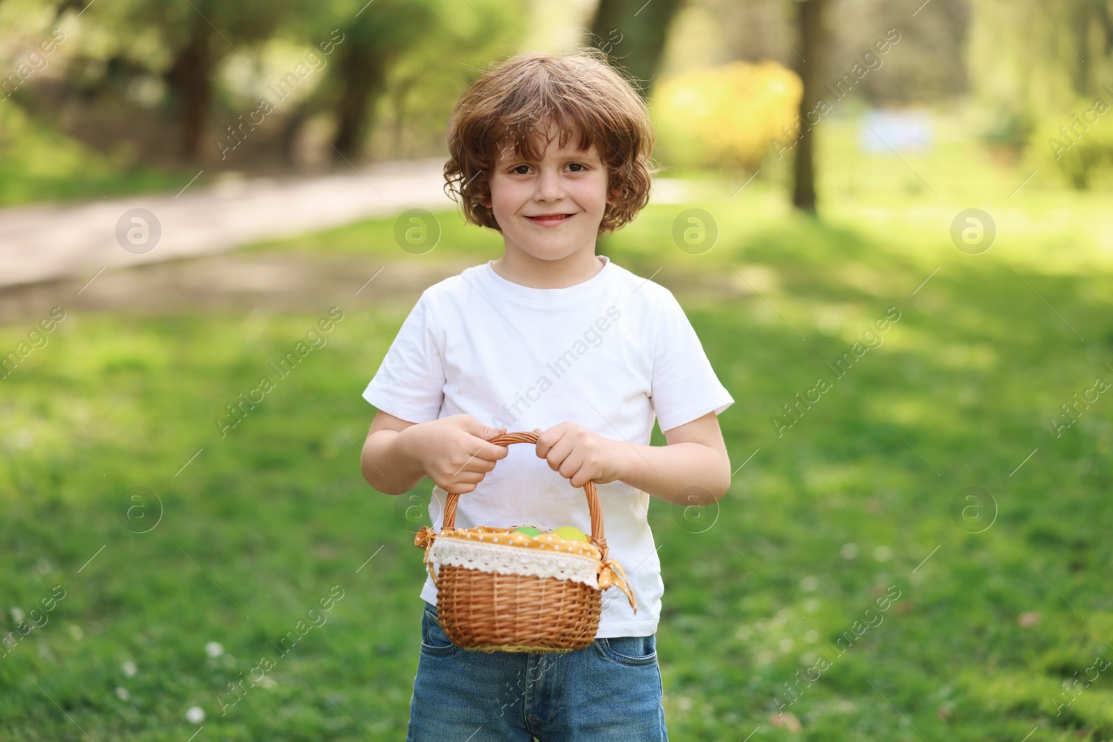 Photo of Easter celebration. Cute little boy holding wicker basket outdoors