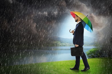 Image of Businessman with umbrella under heavy rain. Insurance concept