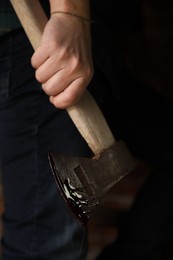 Photo of Man holding bloody axe indoors, closeup view