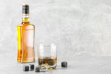 Photo of Whiskey stones and drink on light marble table. Space for text