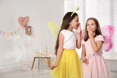 Photo of Cute little girls wearing fairy costumes in decorated room. Space for text