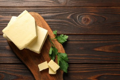 Tasty butter and parsley on wooden table, top view. Space for text