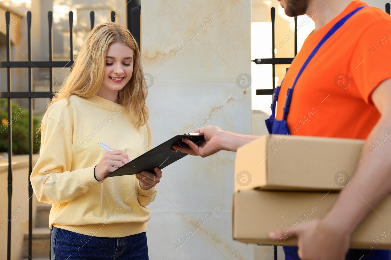 Photo of Woman signing order receipt outdoors. Courier delivery