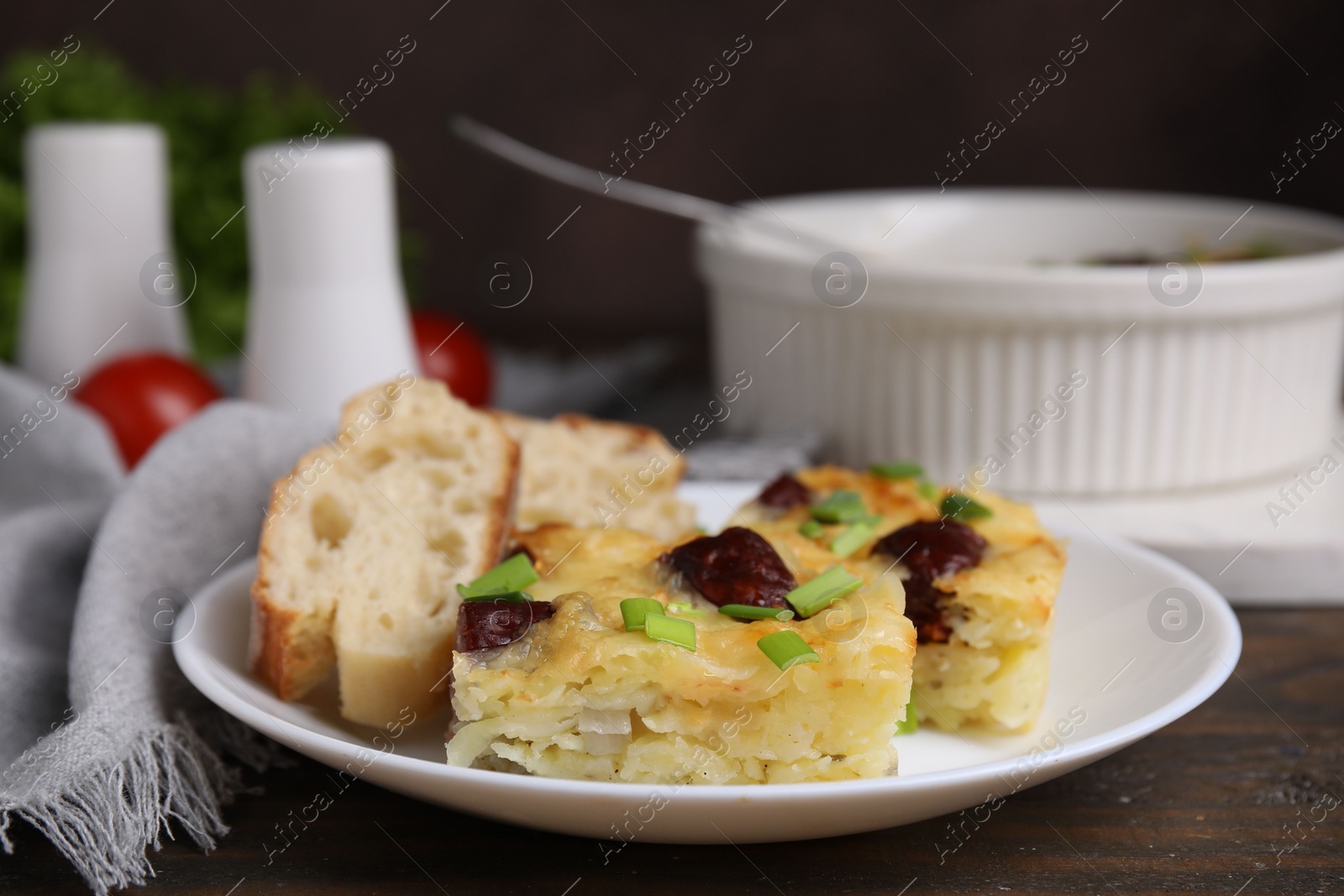 Photo of Tasty sausage casserole with green onion and bread on wooden table, closeup