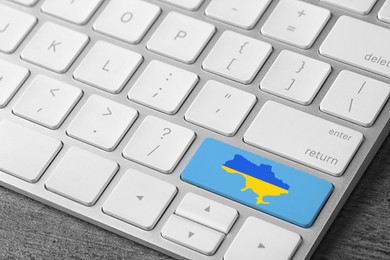 Button with map of Ukraine in colors of national flag on keyboard, closeup view