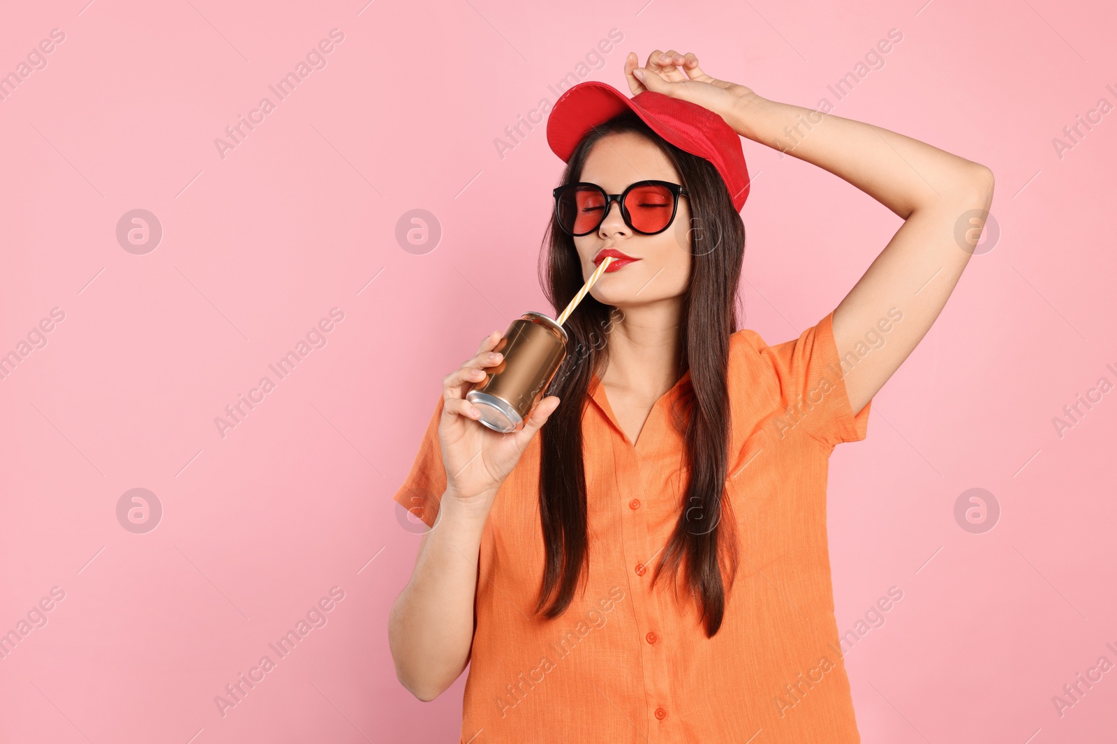 Photo of Beautiful young woman drinking from tin can on pink background. Space for text