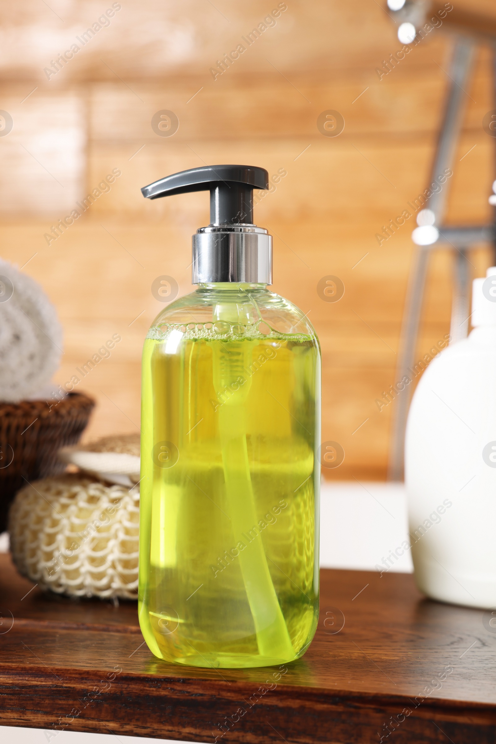 Photo of Dispenser of liquid soap on wooden board in bathroom