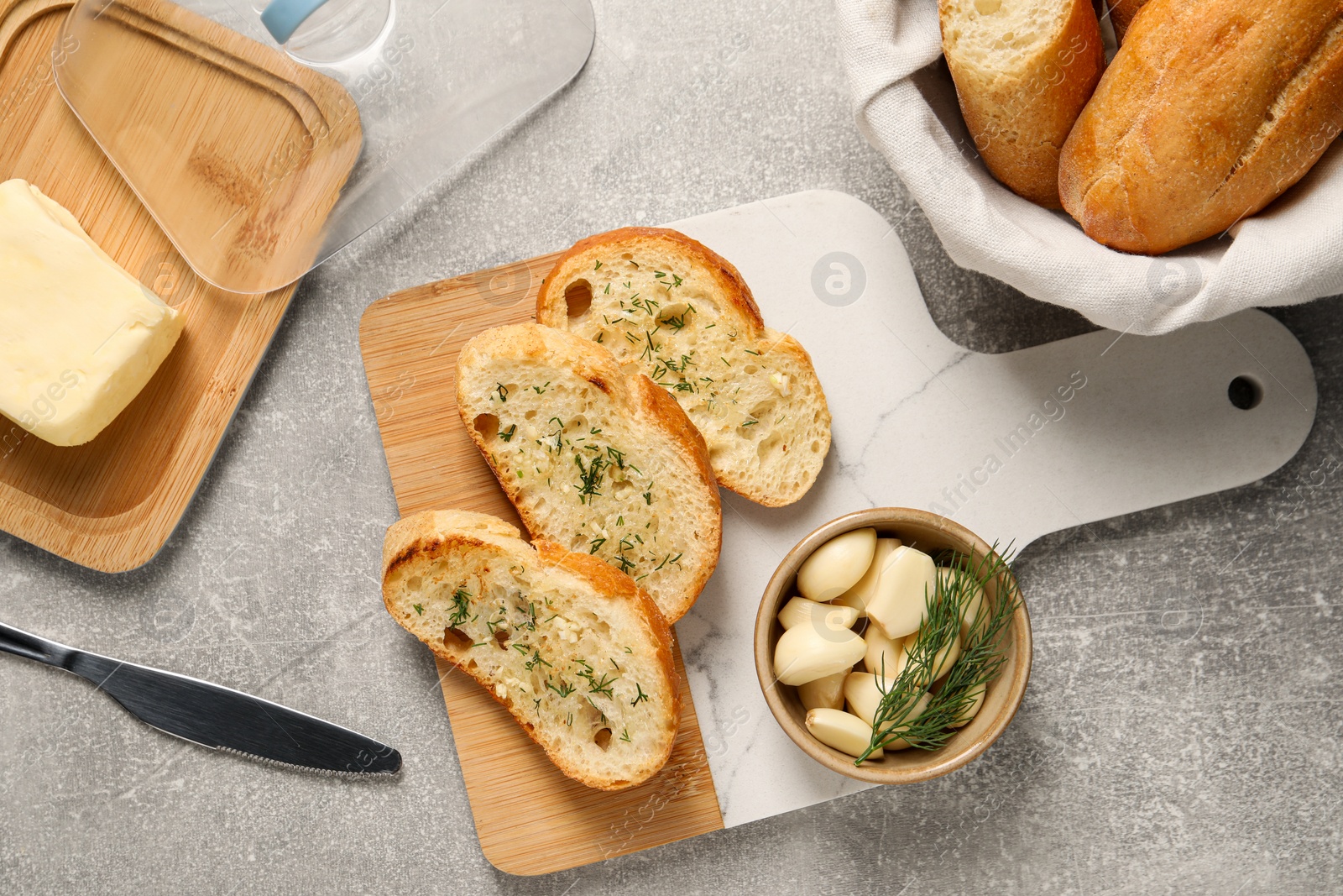 Photo of Tasty baguette with garlic and dill served on light grey table, flat lay