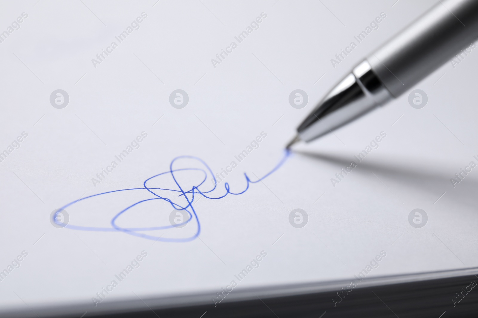 Photo of Signing on sheet of white paper with pen, closeup
