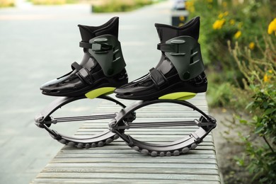 Photo of Stylish kangoo jumping boots on wooden bench outdoors