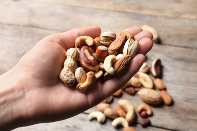 Woman holding organic mixed nuts over table, closeup