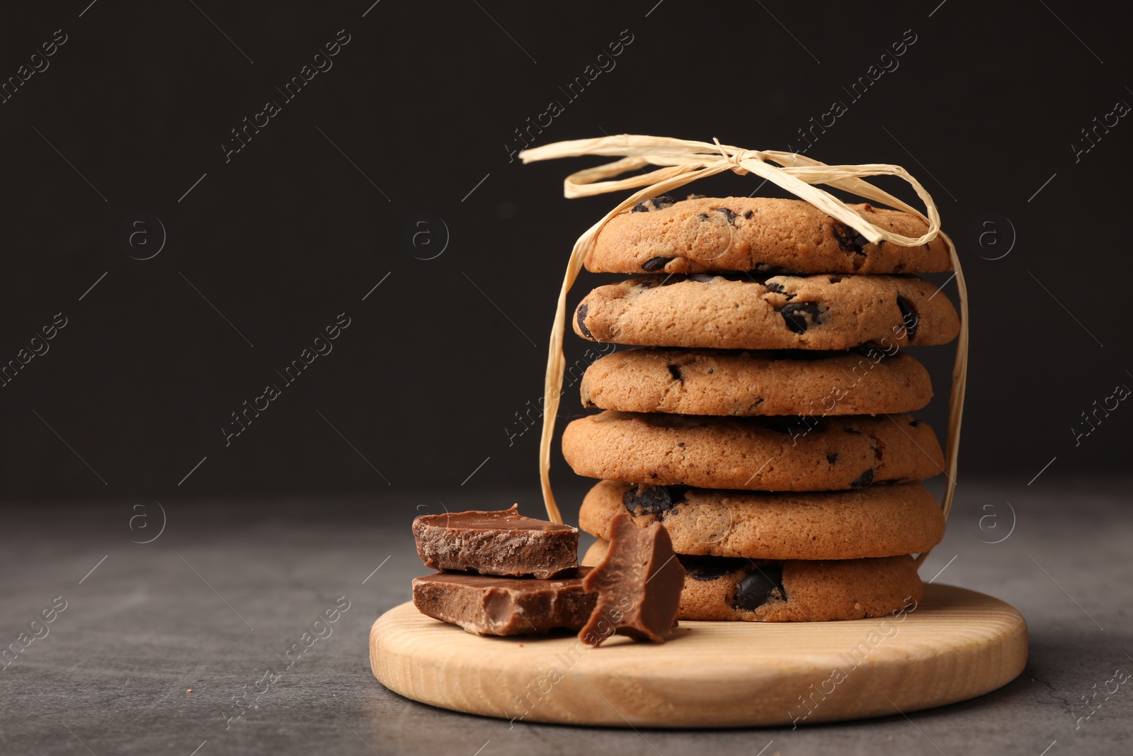 Photo of Stack of delicious chocolate chip cookies on grey table. Space for text