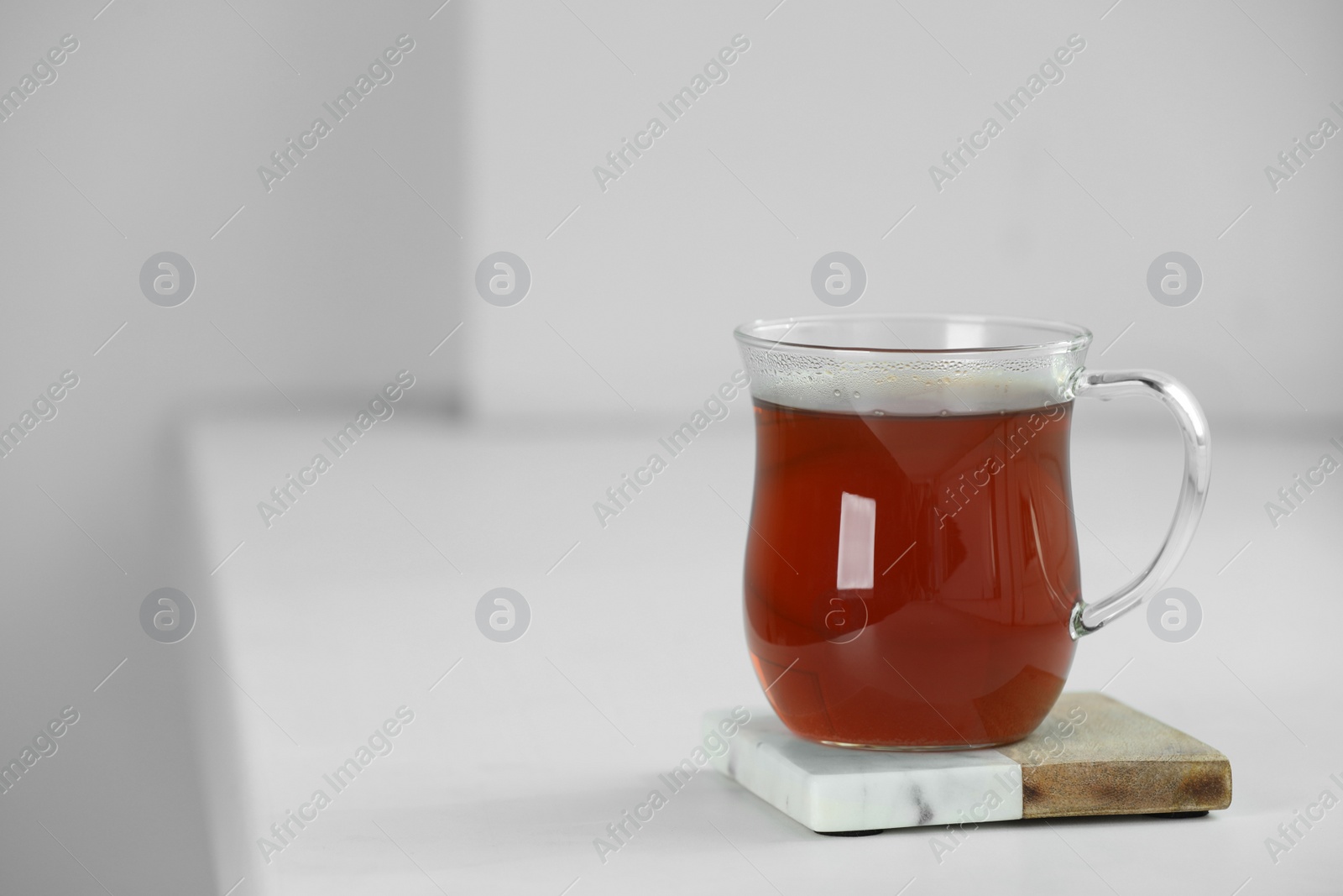 Photo of Cup of hot tea on white sill near window. Space for text