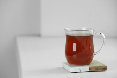 Cup of hot tea on white sill near window. Space for text