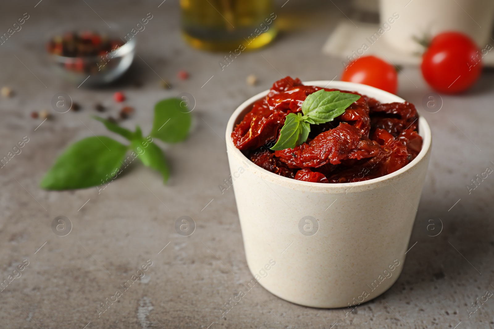 Photo of Bowl with sun dried tomatoes on gray table