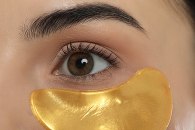 Photo of Young woman with golden under eye patch, closeup