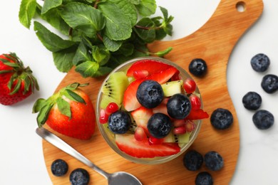 Photo of Healthy breakfast. Delicious fruit salad in glass and ingredients on white table, flat lay