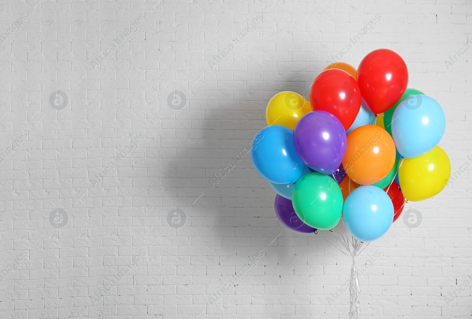 Photo of Bunch of bright balloons and space for text against brick wall