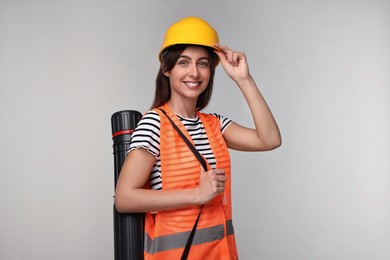 Architect in hard hat with tube on light grey background
