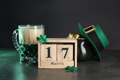 St. Patrick's day celebrating on March 17. Green beer, wooden block calendar, leprechaun hat, pot of gold and decorative clover leaves on grey table