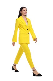Photo of Beautiful businesswoman in yellow suit walking on white background
