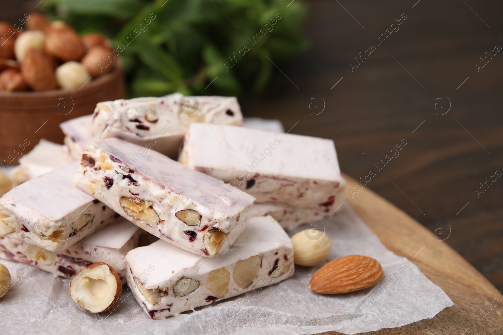 Photo of Pieces of delicious nutty nougat on wooden board, closeup