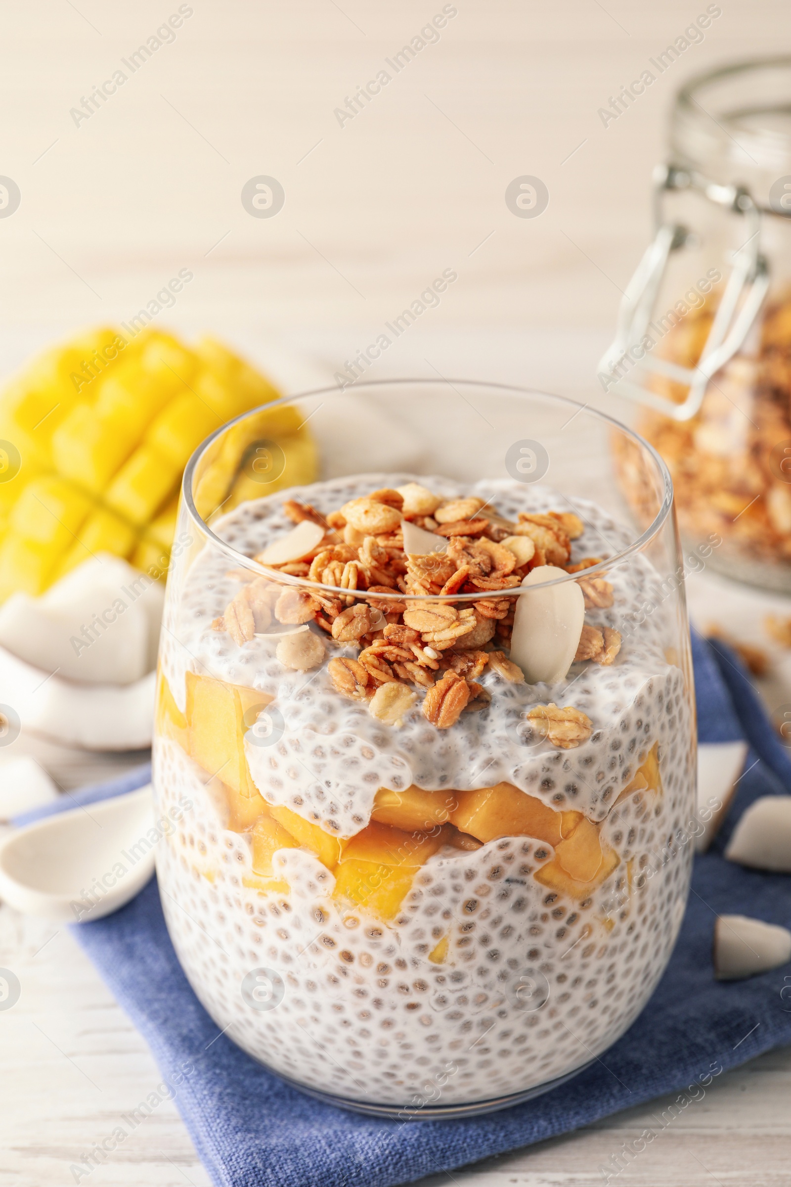 Photo of Delicious chia pudding with granola and mango on white table