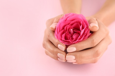 Closeup view of woman with rose on color background, space for text. Spa treatment