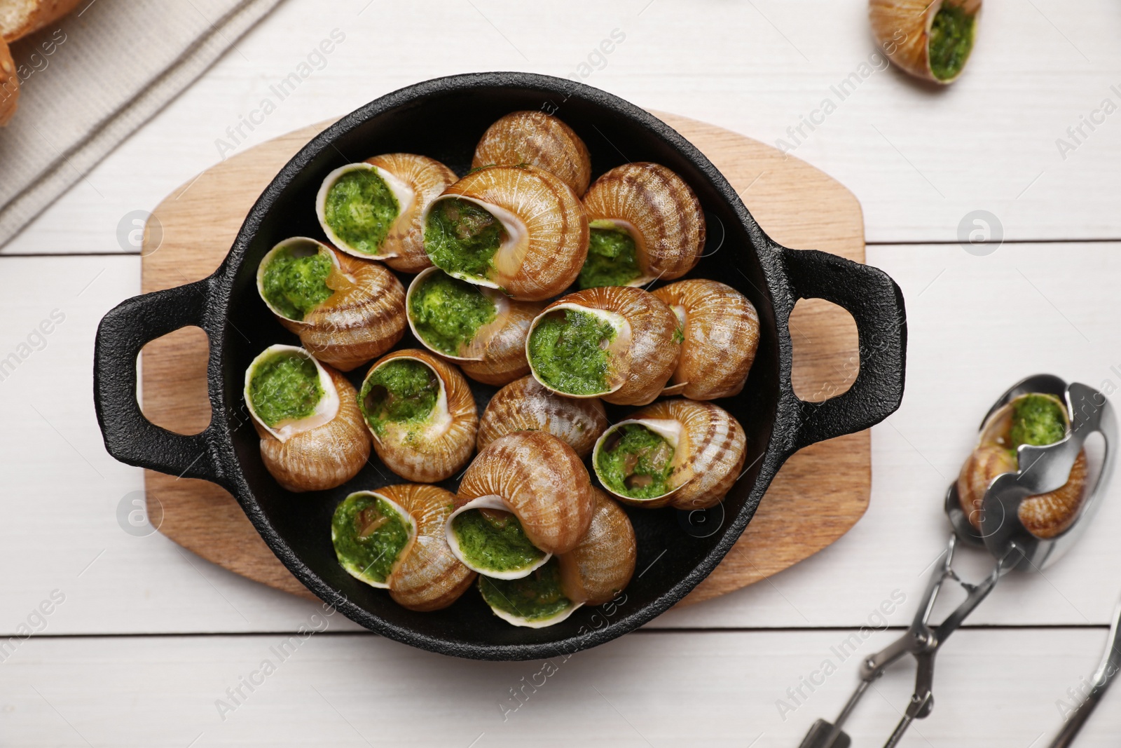 Photo of Delicious cooked snails served on white wooden table, flat lay