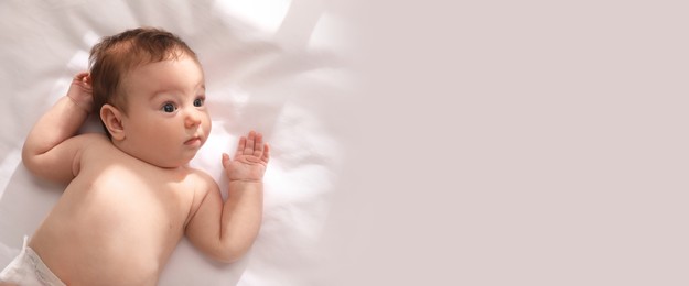 Image of Cute little baby on bed, top view with space for text. Banner design