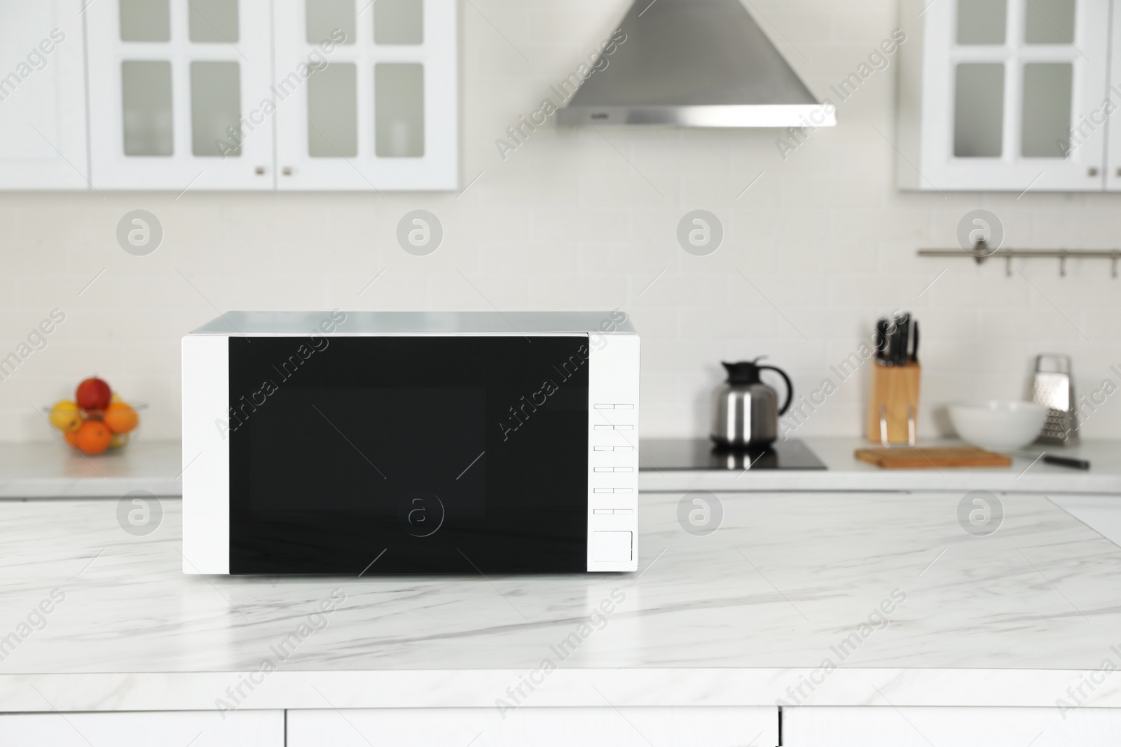 Photo of Modern microwave oven on white table in kitchen, space for text