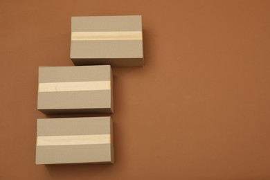 Photo of Cardboard boxes on brown background, flat lay. Space for text