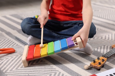 Photo of Little boy playing toy xylophone at home, closeup